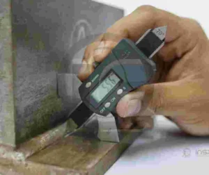 Técnica de inspeção por partículas magnéticas sendo aplicada em material metálico.