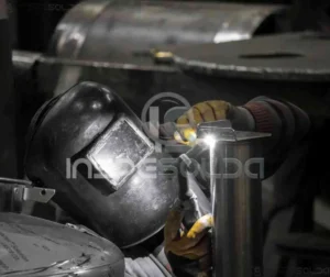 Detalhe de processo de soldagem em ambiente industrial com ênfase nos componentes metálicos.