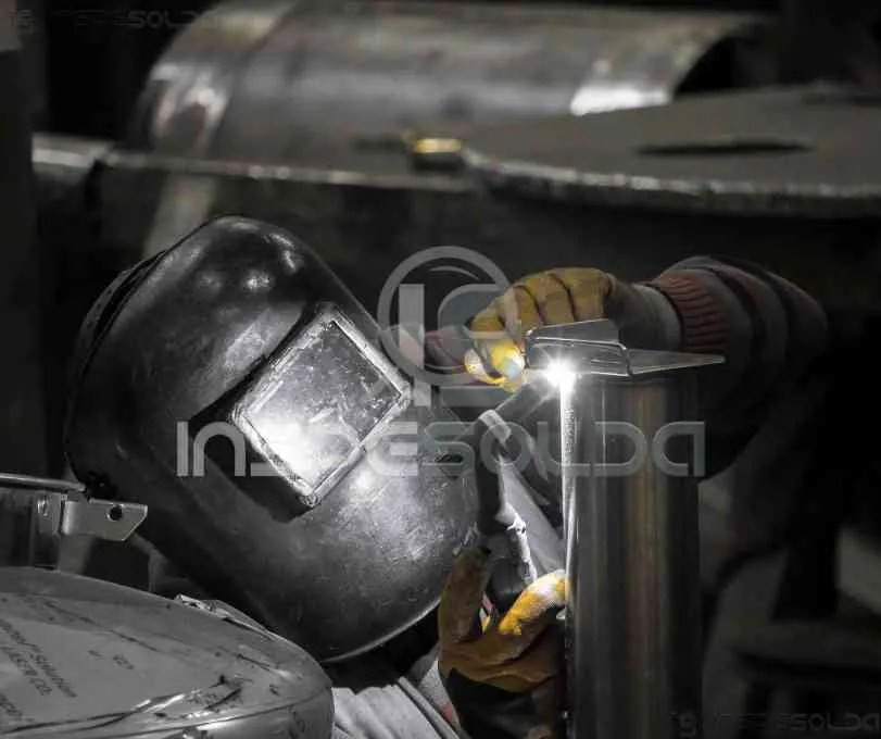 Detalhe de processo de soldagem em ambiente industrial com ênfase nos componentes metálicos.