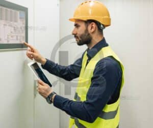 Engenheiro industrial com EPI analisando painel técnico em ambiente fabril.