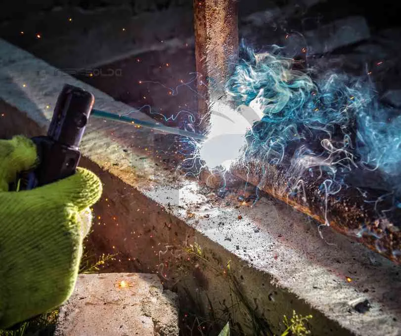 Processo de fabricação com eletrodo revestido em andamento, com fagulhas e arco elétrico visível.