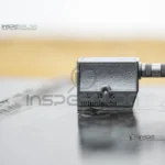 Soldagem Por Ultrassom 30 Peça metálica sendo analisada com o método de inspeção por ultrassom em um ambiente industrial.