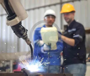 Soldador operando equipamento de soldagem automatizada em ambiente industrial.