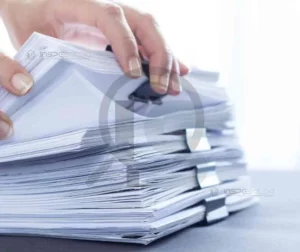 Pilha de documentos sendo organizada por um profissional.