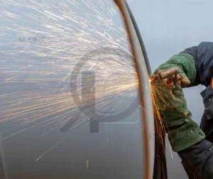Trabalhador utilizando esmerilhadeira para acabamento e redução de respingos na soldagem.