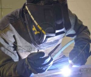 Qualificação de Soldadores/Operadores de Solda 29 Soldador avançado executando uma solda com segurança e precisão, demonstrando um caso de sucesso em projeto industrial.