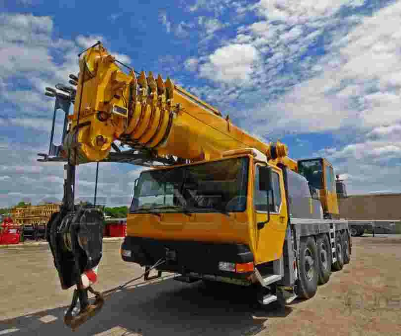 Laudo de Gancho de Moitão de Guindaste 2 Guindaste industrial amarelo estacionado em canteiro de obras.