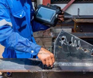 Técnico realizando inspeção em revestimento metálico com equipamento especializado.
