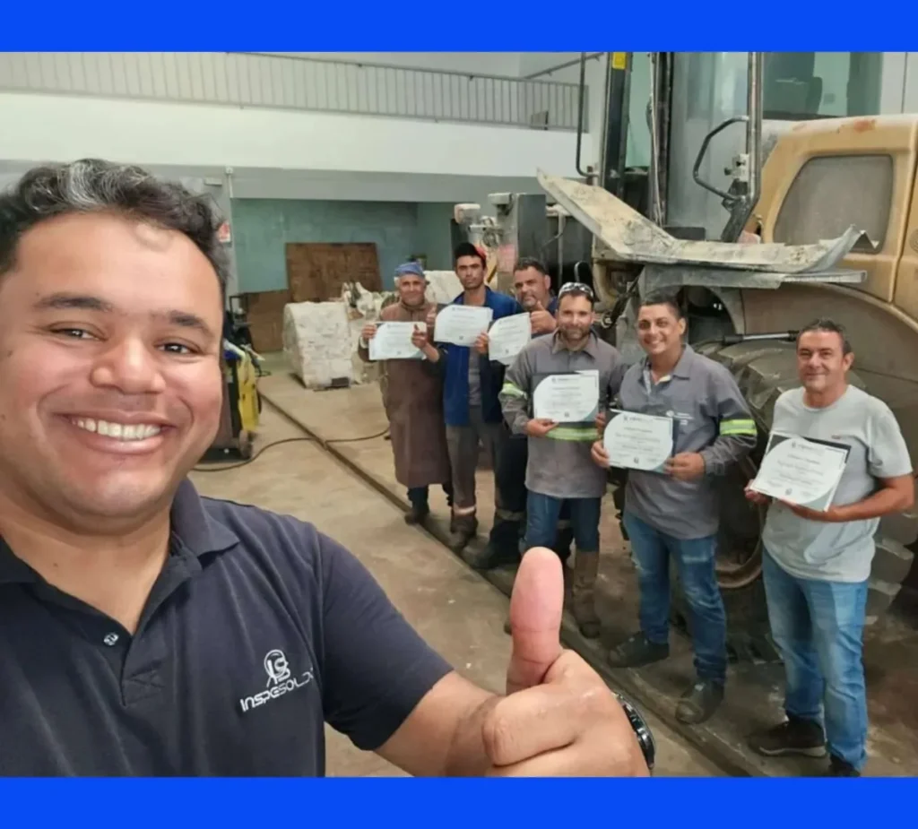 Henrique Reis em selfie industrial com equipe segurando certificados e equipamentos ao fundo.