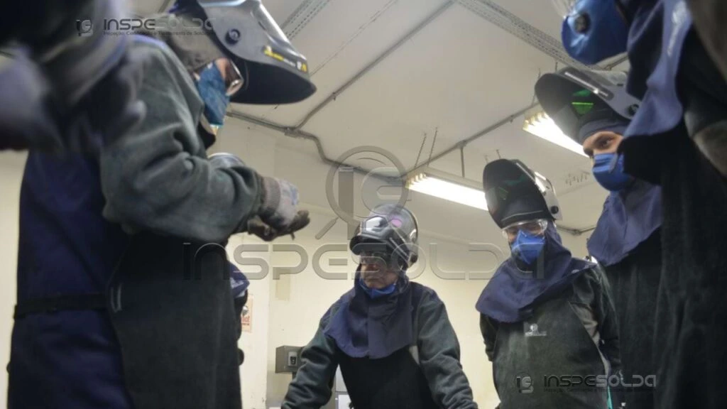 home-treinamento-de-soldagem-pratico Soldadores treinam em ambiente controlado, com máscaras e aventais para segurança na soldagem.