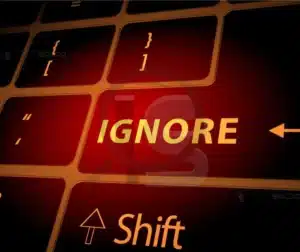 Tecla vermelha com a palavra "IGNORE", simbolizando o risco de ignorar normas e padrões na indústria.