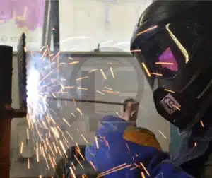 Inspetor de soldagem avaliando uma junta metálica durante um processo de inspeção industrial.