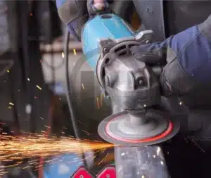 Trabalhador utilizando uma ferramenta para preparação de superfície metálica antes da soldagem.