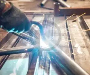 Qualificação de Soldagem para Reduzir Falhas 3 Profissional realizando soldagem, representando a importância da qualificação de procedimentos para garantir a qualidade e reduzir riscos em processos industriais.